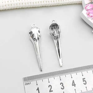 Macro detail of bird skull pendants in silver alloy with 4.5cm ruler for size scale
