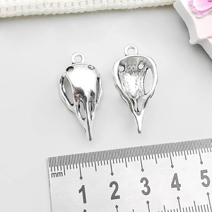 Macro detail of antique silver bird skull pendants with ruler showing 2.6cm length