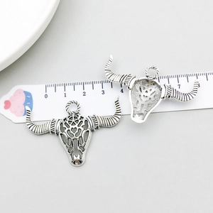 Detailed macro view of vintage silver bull skull pendants with hollow design and size scale