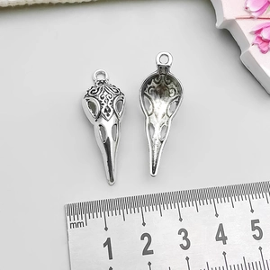 Detail showing front and back of antique silver bird skull pendant with baroque patterns