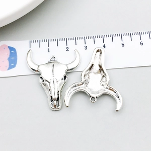Macro detail of vintage silver bull skull charms showing textured finish and loop