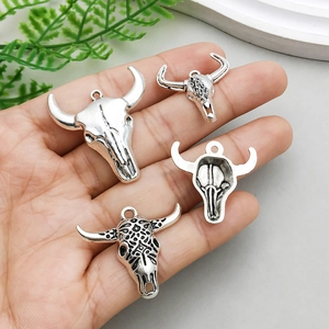 Set of four vintage silver bull skull pendants with intricate metal engravings held in hand