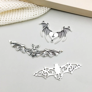 Close-up of antique silver bat pendants featuring heart cross and hollow wing designs