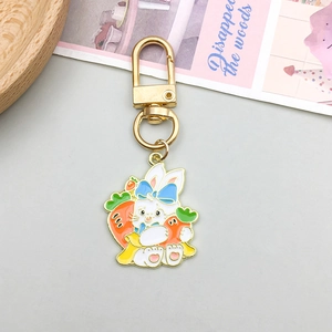 Detail of cartoon white rabbit enamel charm with carrots and golden snap hook fastener