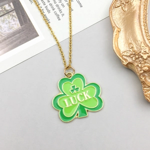 Vue détaillée du pendentif trèfle en émail vert avec texte Luck et chaîne dorée