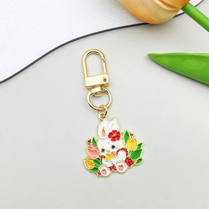 Détail du pendentif lapin en émail coloré avec tulipes et crochet mousqueton doré