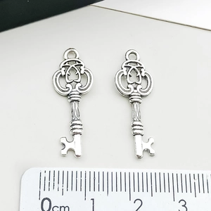 Détail de pendentifs clés argentés rétro avec motifs évidés et échelle de taille