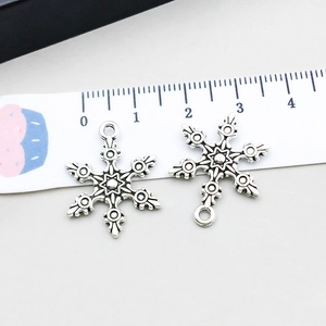 Detail of vintage silver snowflake alloy pendants for DIY jewelry with measurement scale