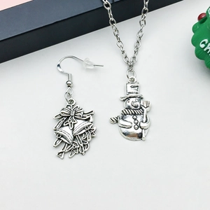 Detail of antique silver Christmas jewelry set with snowman pendant and bell earrings