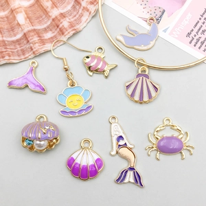 Primer plano de colgantes marinos de esmalte morado y conchas para joyería artesanal