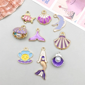 Detalle de dijes esmaltados en color púrpura con formas marinas para joyería artesanal DIY