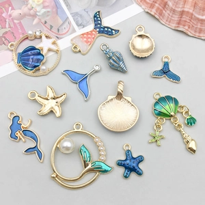 Platliggende weergave van blauwe emaille oceaanbedeltjes met parels en strass-steentjes