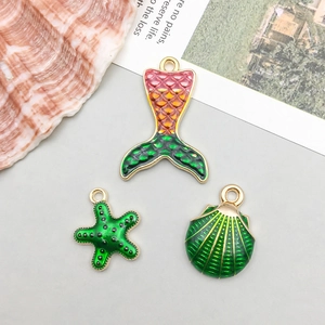 Detail of mermaid tail, starfish, and shell enamel charms for DIY jewelry making