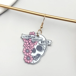 Nahaufnahme von Acryl-Schädel-Ohrring mit rosa Blumen und Goldhaken am Aufsteller