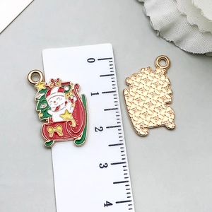 Macro view of Christmas snowman and tree charms with gold textured back and metal ring