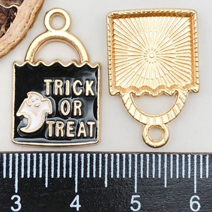 Detailed macro view of black ghost charm with Trick or Treat text and golden back
