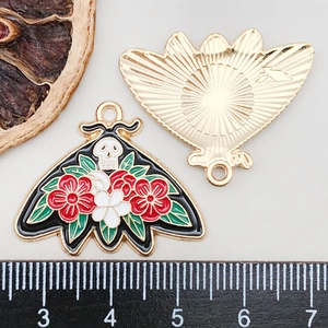 Macro shot of moth pendant showing skull enamel design and sunburst texture back