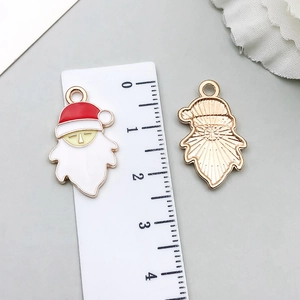 Detail of Santa Claus enamel pendants showing front and textured gold back with a ruler