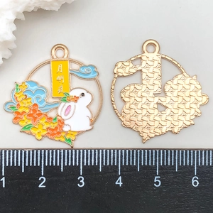 Detail view of rabbit enamel pendants showing front and back with size scale