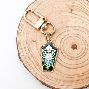 Detail of gothic coffin keychain with skull and rose enamel on a wooden tray