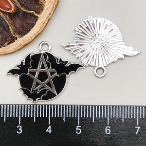 Detail view of pentagram bat charms with a ruler for size measurement and reference