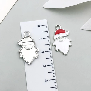 Detalle de colgantes de Papá Noel mostrando escala de 2,5 cm y proceso de esmalte rojo