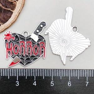 Detail of horror heart pendant with spider web and blood knife on scale ruler