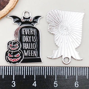 Detail of Halloween tombstone pendant with bat and pumpkin motifs on black enamel