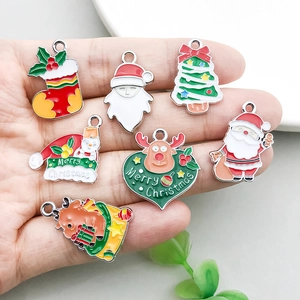 Mano sosteniendo dijes navideños de esmalte de colores para joyería DIY variada