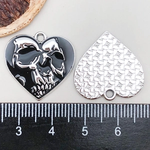 Dettaglio del ciondolo a cuore con teschio in smalto nero e righello di misura