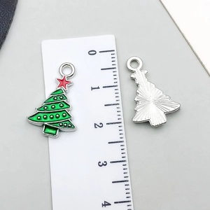 Dettaglio di ciondolo a forma di albero di Natale in smalto verde con misura su righello
