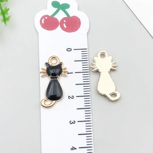 Detail of black enamel cat pendant showing dimensions with a ruler for DIY jewelry crafts