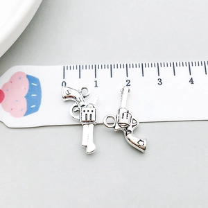 Macro shot of two vintage silver revolver pendants showing size on a ruler scale