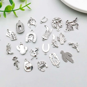 Detail of antique silver cowboy charms including boots, hat, and horseshoe for DIY jewelry