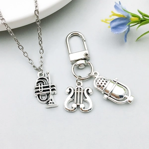 Close-up of antique silver music instrument charms including a lyre harp and microphone