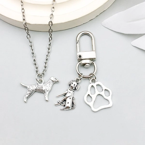 Detailed silver dog pendant and hollow paw print charm on smooth metal keychain