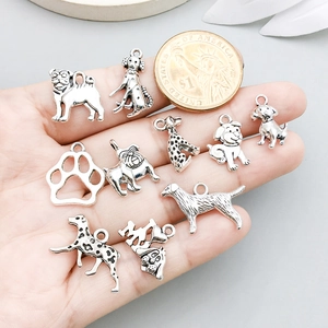 Antique silver dog charms set including paw prints and heart pendant in palm
