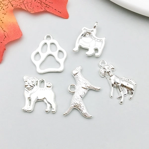 Dettaglio macro di vari ciondoli a forma di cane in argento per creazione gioielli DIY
