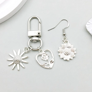 Détails de breloques tournesol et cœur rose sur ensemble porte-clés et boucles d'oreilles