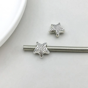 Macro view of vintage silver starfish star charms with dotted texture for DIY jewelry