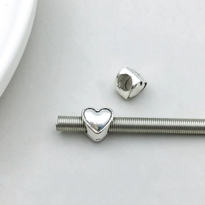 Detailed view of silver heart-shaped charms with large holes for DIY charm bracelets