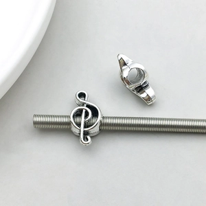 Macro shot of silver alloy treble clef charm for DIY jewelry on a threaded metal rod