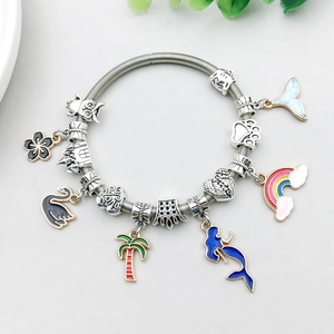 Detailed shot of alloy charms with swan and palm tree pendants on a silver bracelet