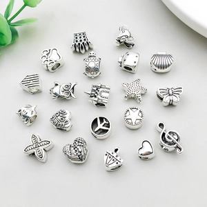 Detailed view of assorted antique silver charms with starfish, crown and heart motifs