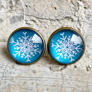 Close-up of vintage bronze stud earrings with blue glass and white snowflake patterns