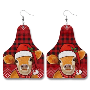 Detail of Christmas earrings featuring a festive cow motif on red black buffalo plaid