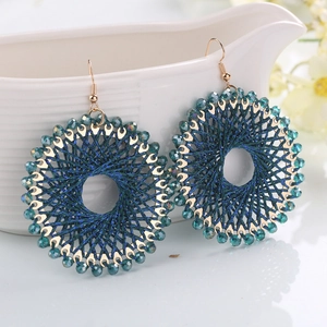 Close-up of bohemian hoop earrings with blue silk weaving and faceted crystal beads