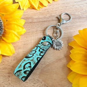 Détail du porte-clés vintage en cuir avec pendentif tournesol sur un fond en bois