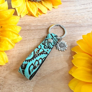 Détail de porte-clés en cuir turquoise vintage avec breloque tournesol et gaufrage floral