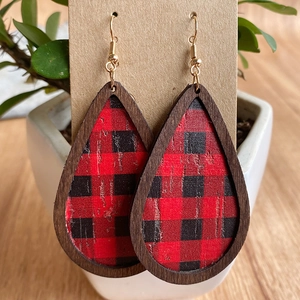 Macro detail of wooden teardrop earrings featuring red and black buffalo plaid textures